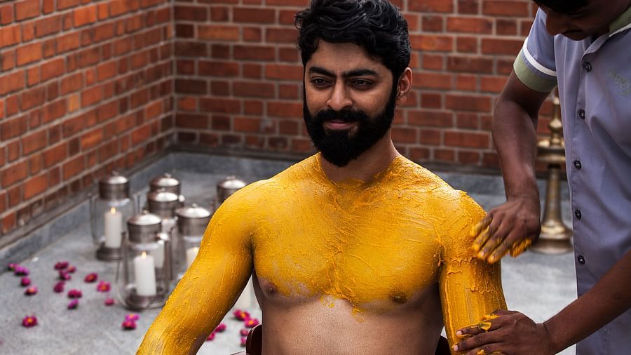 A person with yellow markings on their body, brick wall background - Shreyas Retreat