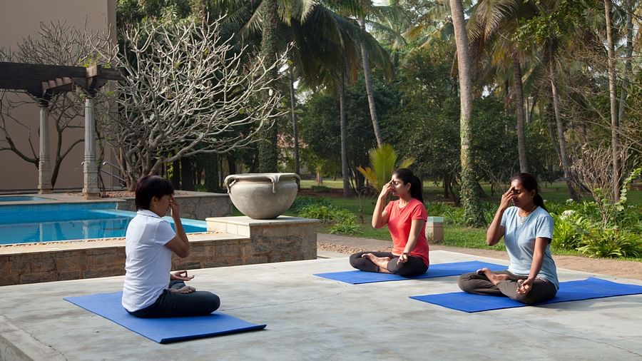 People doing yoga poses on mats by a pool, outdoor setting - Shreyas Retreat
