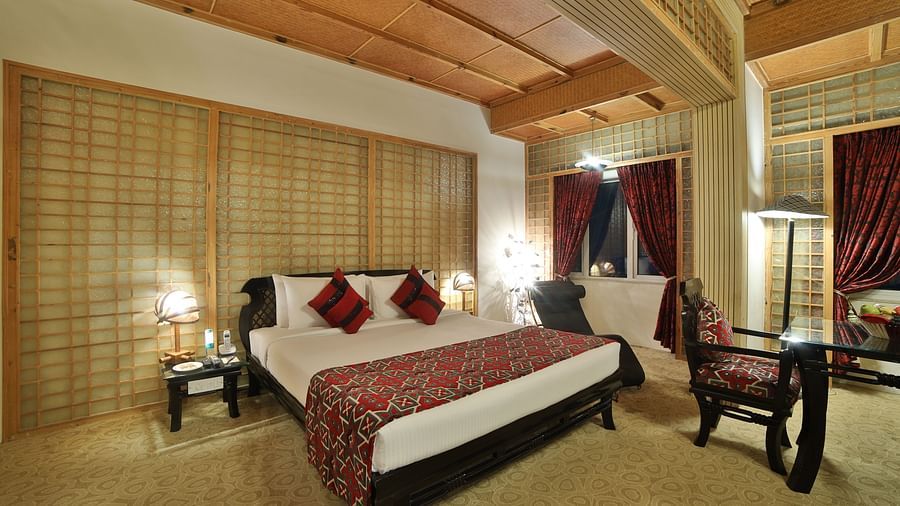 A luxurious hotel room with a richly patterned bedspread, elegant wooden furniture, and warm lighting A grand hotel suite with an opulent red and white decor, large bed, and seating area, reflecting a traditional style at Sitara Luxury Hotel in Hyderabad n