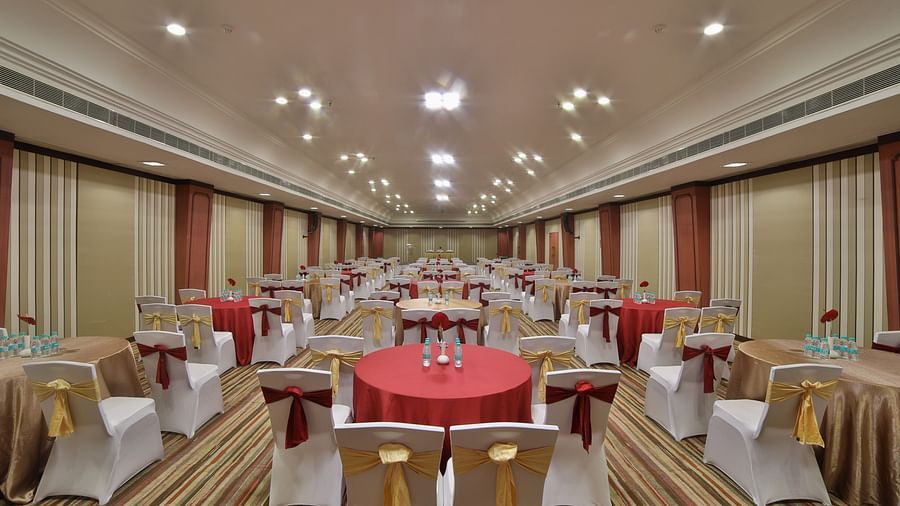  Seating arrangement in Terrace Hall A grand hotel suite with an opulent red and white decor, large bed, and seating area, reflecting a traditional style at Sitara Luxury Hotel in Hyderabad near Ramoji Film City.