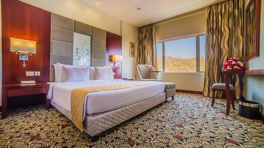 A well-appointed hotel room with a large bed, modern amenities, and a scenic view from the window at  Sitara Luxury Hotel in Hyderabad near Ramoji Film City.