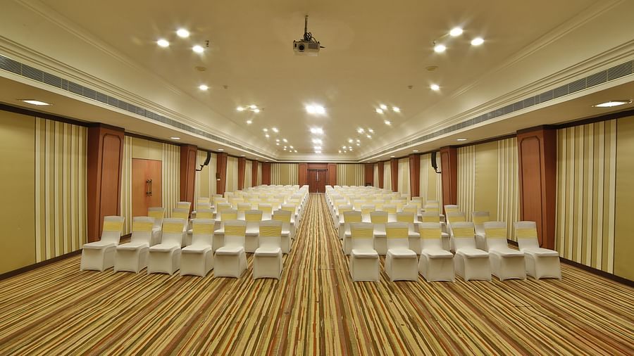  Seating arrangement in Terrace Hall A grand hotel suite with an opulent red and white decor, large bed, and seating area, reflecting a traditional style at Sitara Luxury Hotel in Hyderabad near Ramoji Film City.