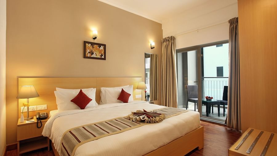 A double bed with side tables and lamps inside Deluxe Room - Starlit Suites, Kochi