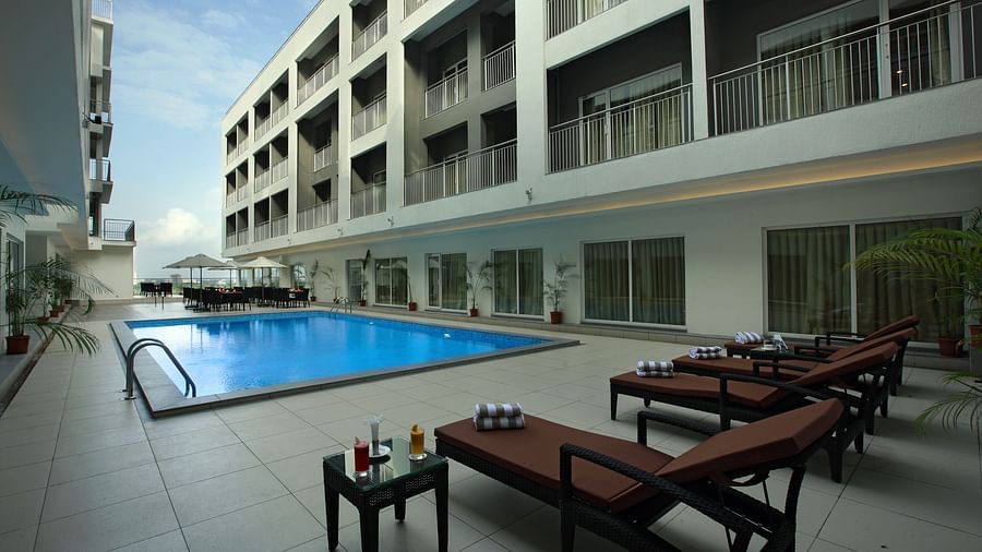 Loungers in front of the swimming pool - Starlit Suites, Kochi