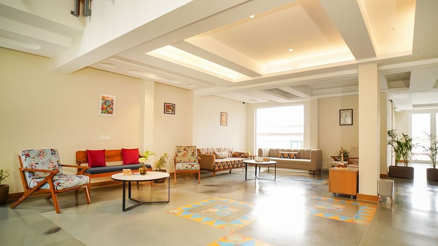 A well-lit hotel lounge area furnished with comfortable sofas and chairs, leading towards a reception area | Sukama Resort & Spa, Nainital