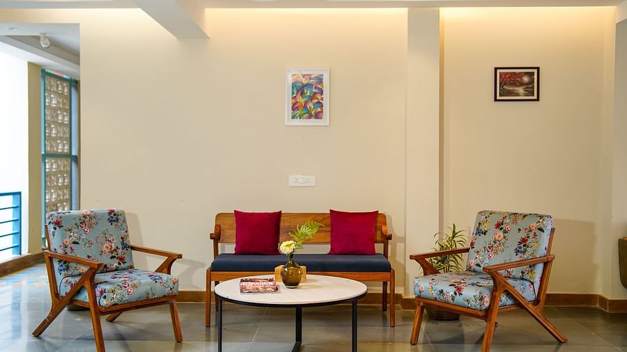 Lobby area features a colourful sofa flanked by two patterned armchairs, centred around a round coffee table, with artwork on the wall and warm lighting | Sukama Resort & Spa, Nainital