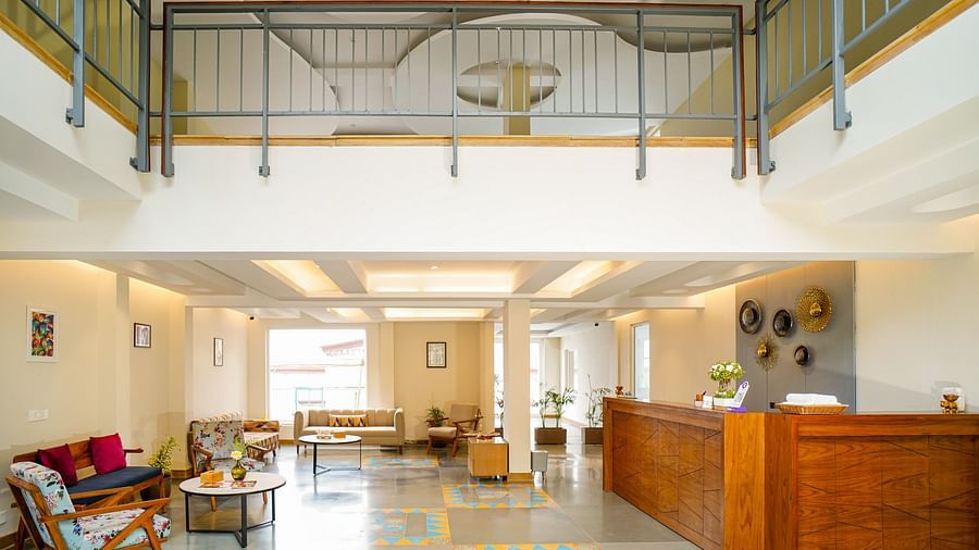 An expansive hotel lobby showcasing a grand staircase, a reception desk, and various seating areas | Sukama Resort & Spa, Nainital