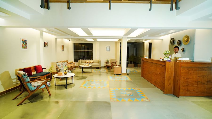 A wide view of a hotel lobby featuring a long reception desk and multiple seating arrangements | Sukama Resort & Spa, Nainital