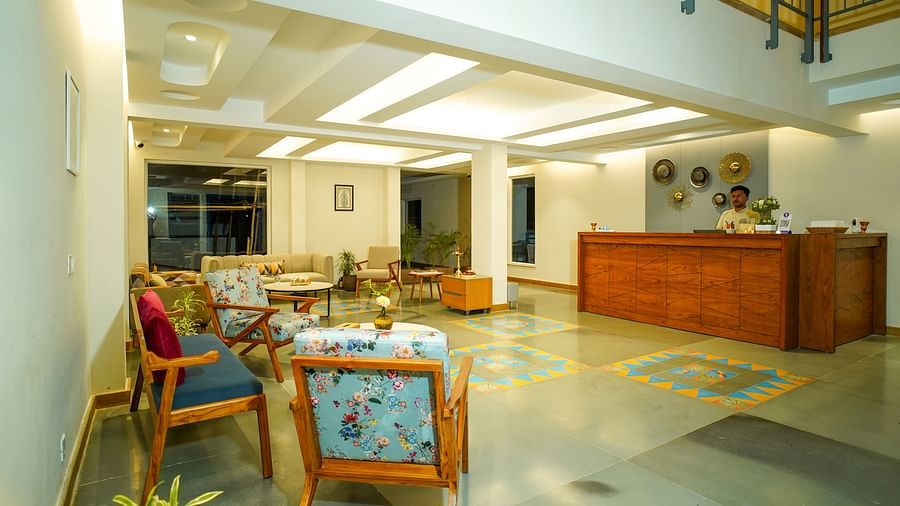An interior view of a hotel common area with dining tables and chairs, and a reception desk in the background | Sukama Resort & Spa, Nainital