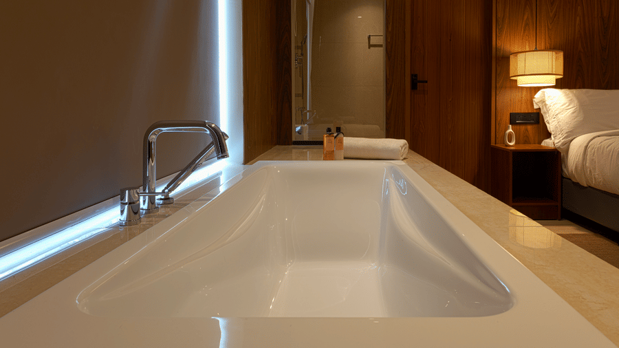 Bathroom at SUKAVI with a large white built-in bathtub.