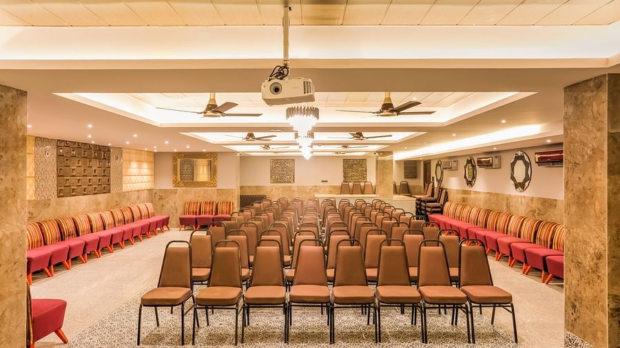 Banquet hall with chairs neatly arranged in rows, illuminated by warm lighting and complemented by overhead ceiling lights