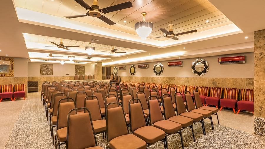  Diagonal view of the banquet hall, showcasing chairs meticulously arranged in rows, bathed in warm lighting and enhanced by overhead ceiling lights