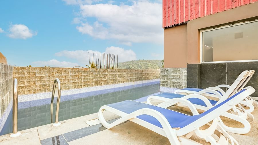  Pool area featuring a reclining chair nearby, set against a backdrop of a partly cloudy sky