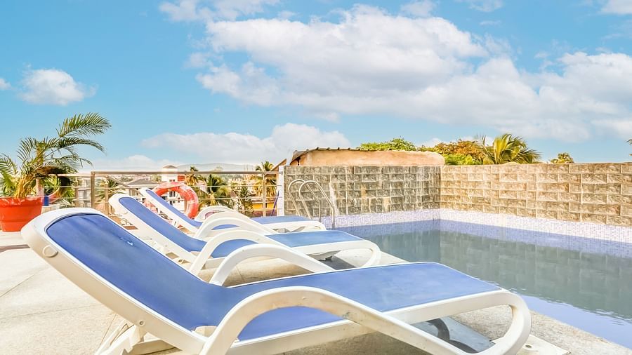  Pool area featuring a reclining chair nearby, set against a backdrop of a partly cloudy sky