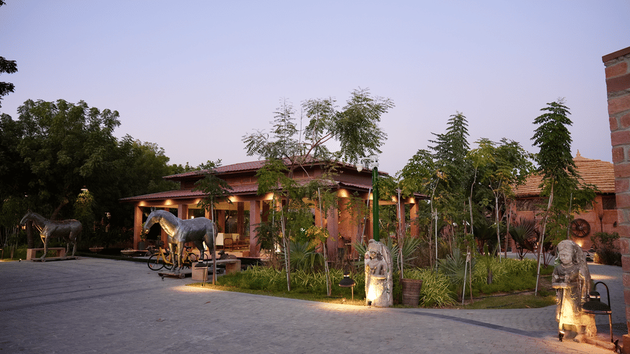Facade of Surpura Bagh with trees surrounding it and a pathway leading to the reception under evening sky