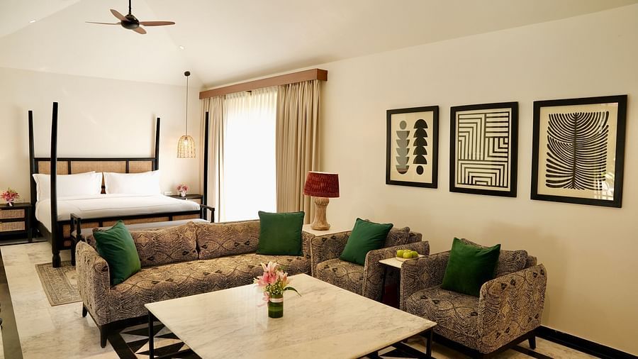 A room with a bed and a seating area adorned with frames at Surpura Bagh.