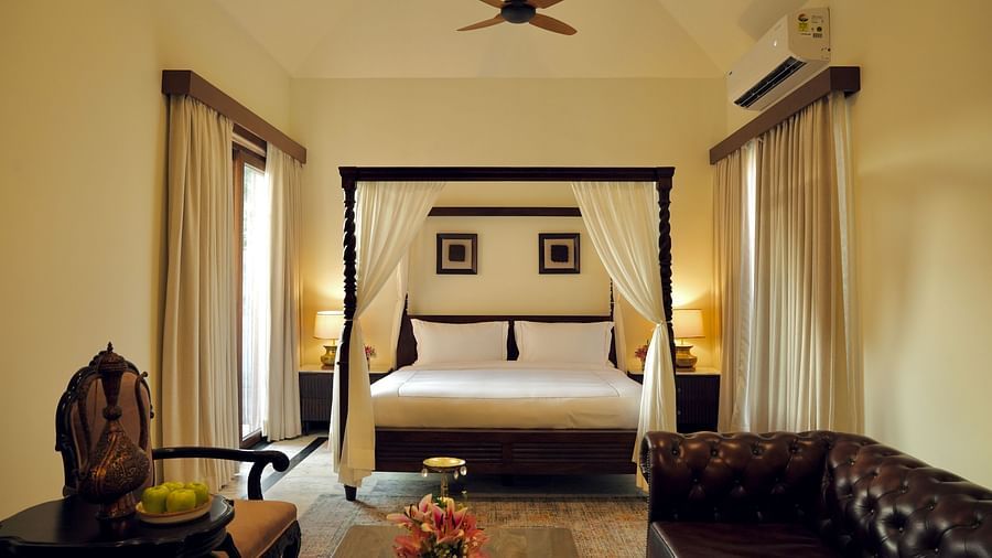 A room with a bed and a seating area in front of it at Surpura Bagh.