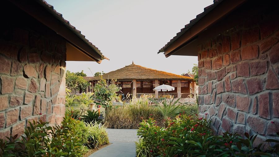 A pathway with villas on both side and one in front, made of brick walls and clay roof with around.
