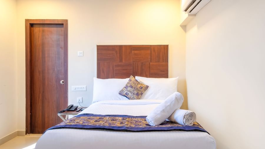 Comfortable bedroom with double bed patterned runner fresh linens and air-conditioning in a welcoming setting at Swarna's The Capital.