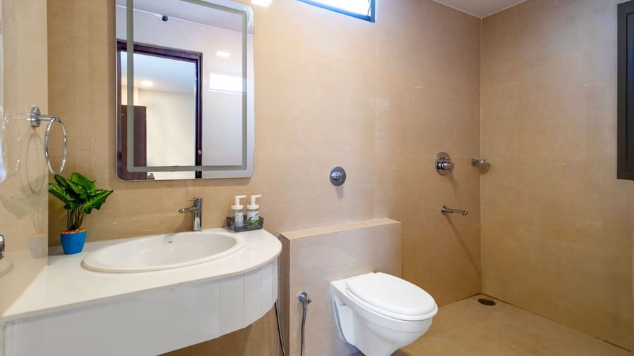 Spacious bathroom with modern fittings a wall mirror wash basin and toilet offering a clean and well maintained space at Swarna's The Capital.