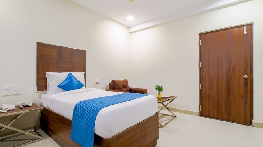 Elegant twin bedroom with wooden furniture soft lighting bedside tables and blue accents at Swarna's The Capital.