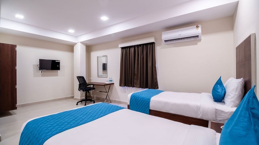 Stylish room with twin beds blue decor study desk television air-conditioning and soft lighting at Swarna's The Capital.