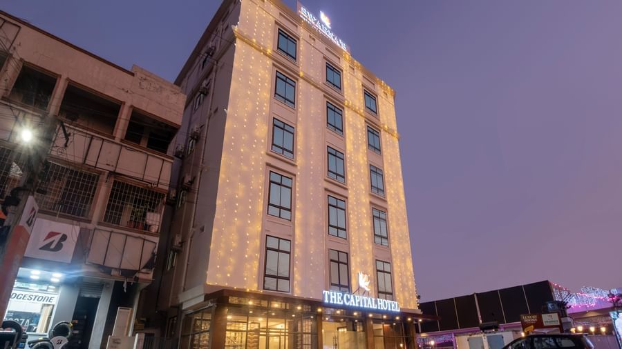 Evening exterior view of Swarna's The Capital with illuminated facade and welcoming entrance.