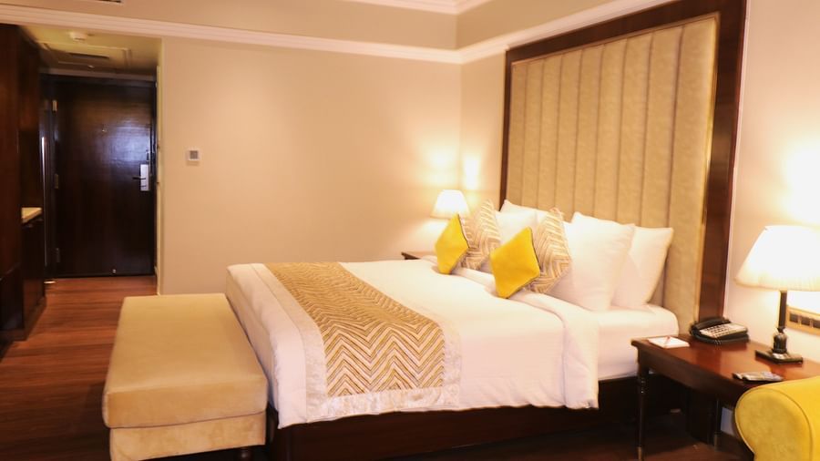 Club Room room at Swosti Premium, Bhubaneswar, with a bed, decorative pillows, and a window with curtains.