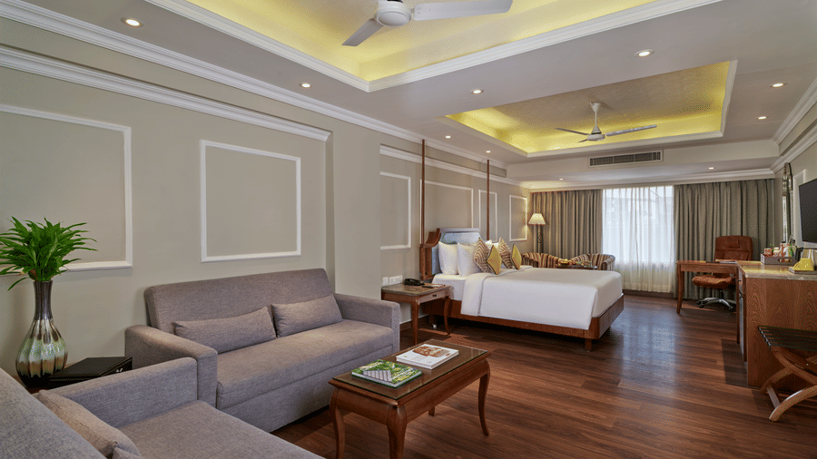 The Executive Suite Room at Swosti Premium, Bhubaneswar, featuring a bed,  bedspreads, pillows, cushions, a fan, tables, and a television.