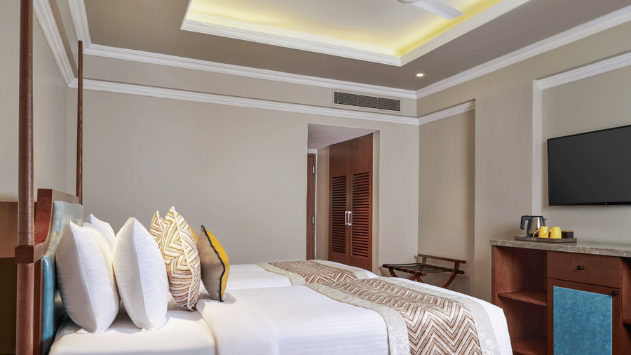 The Premium Twin Room at Swosti Premium, Bhubaneswar, featuring a twin beds, bedspreads, pillows, tables, and a television.