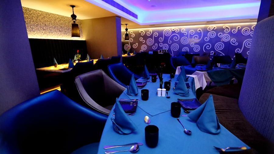 Image of a dining space with seating area and napkins and cutleries on the table at Swosti Grand, Bhubaneswar