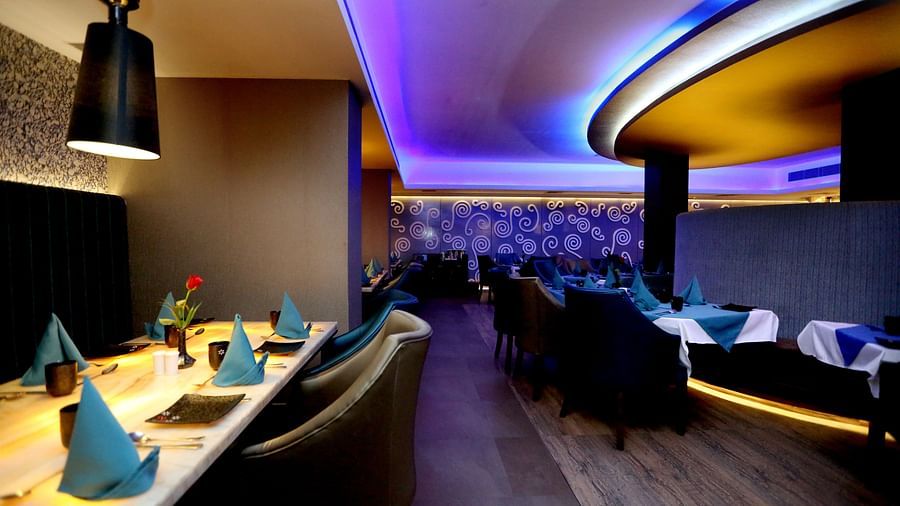 Aqua Restaurant with seating area and fancy ligjt above the tables at Swosti Grand, Bhubaneswar