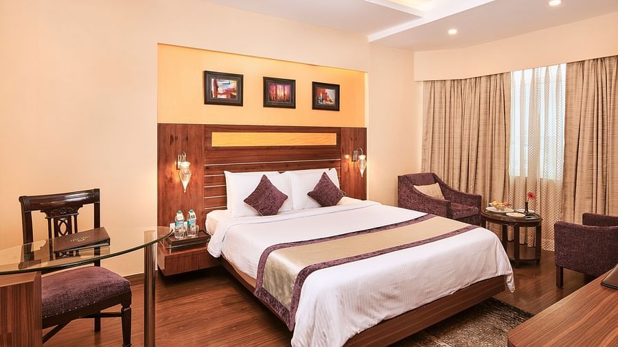 Deluxe Room with bed with frames above it and seating area on both the sides