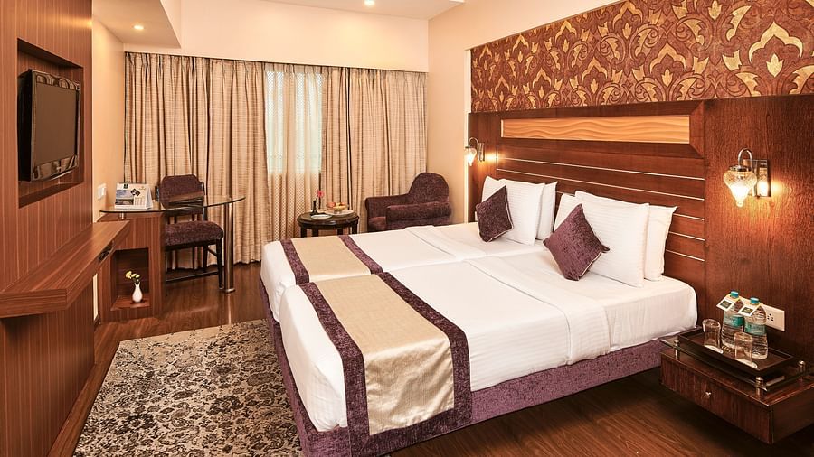 Deluxe Room with twin beds and television in front of it at Swosti Grand, Bhubaneswar