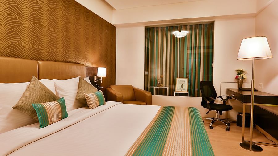 A room with a double bed, a standing lamp and a work desk and chair at T24 Residency, Andheri East, Mumbai