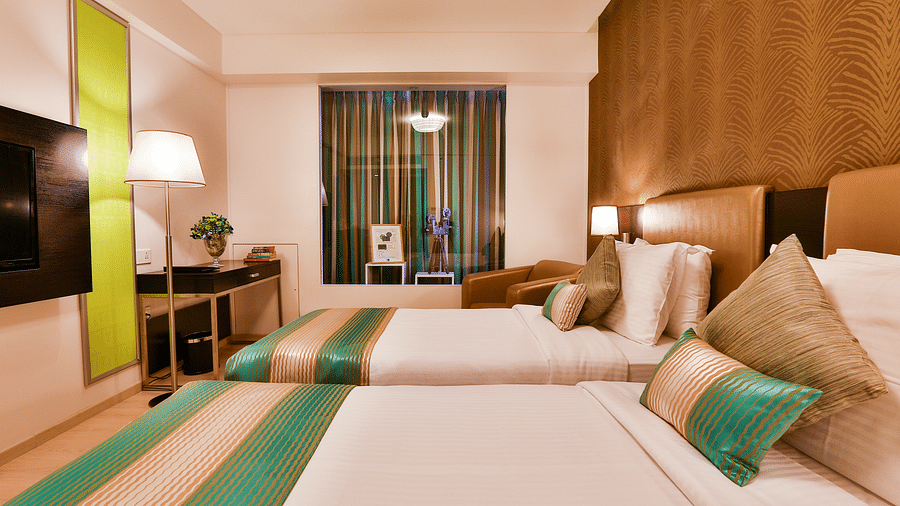 A room with twin beds, standing lamp and a work desk and chair at T24 Residency, Andheri East, Mumbai