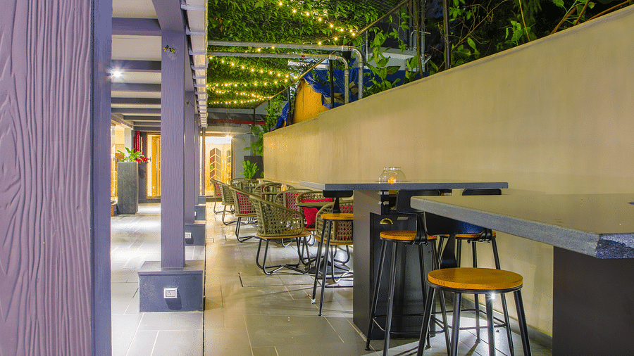 An outdoor dining area with tables and chairs under a wooden pergola  | T24 Retro