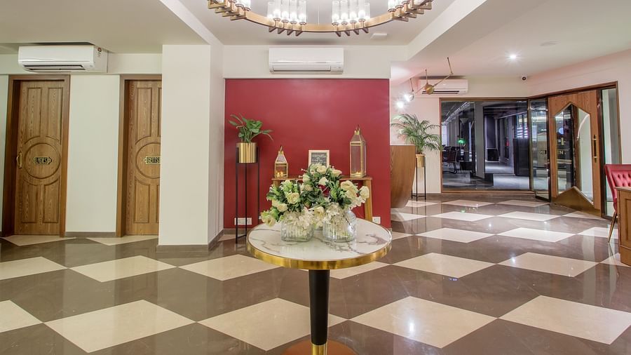 A spacious and elegant hotel lobby with a grand chandelier and a marble-topped table | T24 Retro