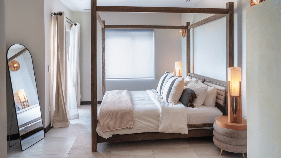 A king bed with white bedding, bedside tables, curtains, a wooden bench, and wall-mounted lighting in Suite 35 at Tamarind Hills Resort and Villas.