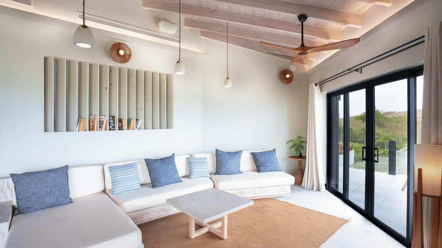 A spacious living area with sofas, cushions, a coffee table, pendant lights, and large sliding glass doors in Suite 35 at Tamarind Hills Resort and Villas.