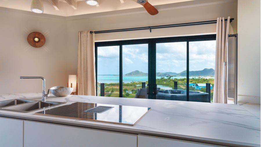 An open-plan kitchen with a countertop and sink, ceiling fan, and large sliding glass doors overlooking the outdoor area at Suite 35, Tamarind Hills Resort and Villas.