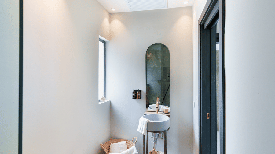 A bright interior passageway with an arched mirror, a small table with a lamp, and a doorway in Suite 35 at Tamarind Hills Resort and Villas.