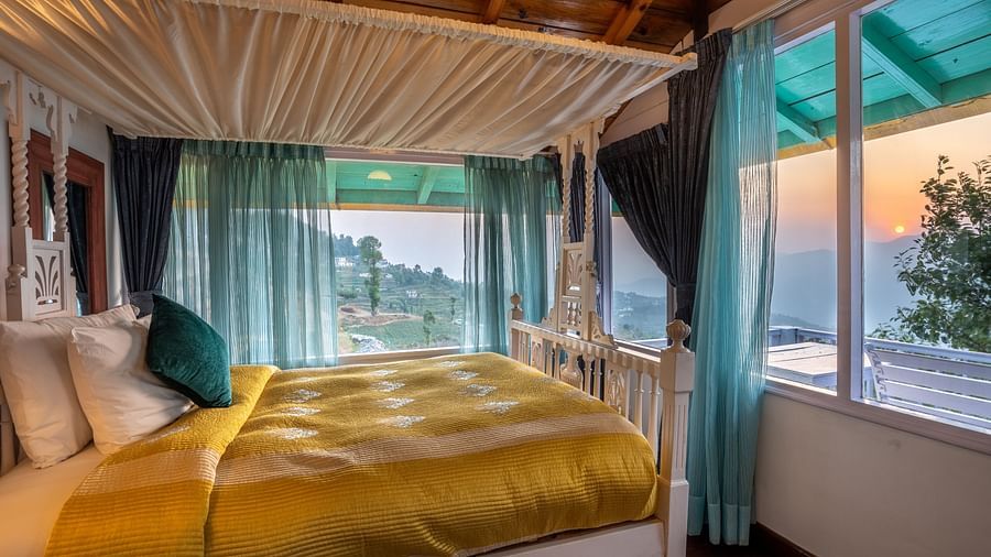 side view of a room with a bed and large windows at Te Aroha By Shervani, Mukteshwar 