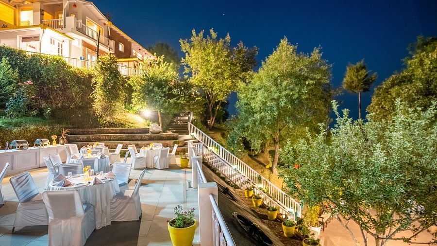 A terrace with a dinning space surrounded by trees at Te Aroha By Shervani, Mukteshwar