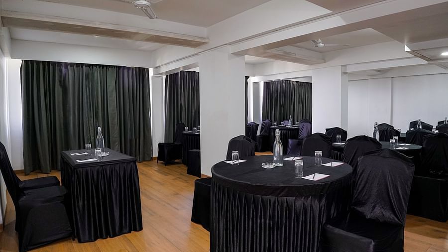 An empty conference room with round tables covered in black cloths - TGI Ameya Grand, Goa