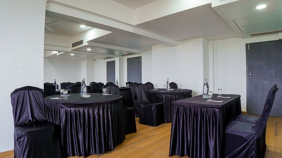 Spacious conference room with round tables and chairs covered in black - TGI Ameya Grand, Goa