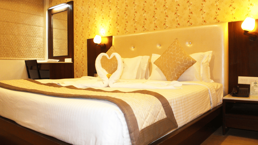 Luxurious bedroom with upholstered headboard, ambient lighting and premium bedding at TGI Apple Inn, Ajmer Road, Jaipur.