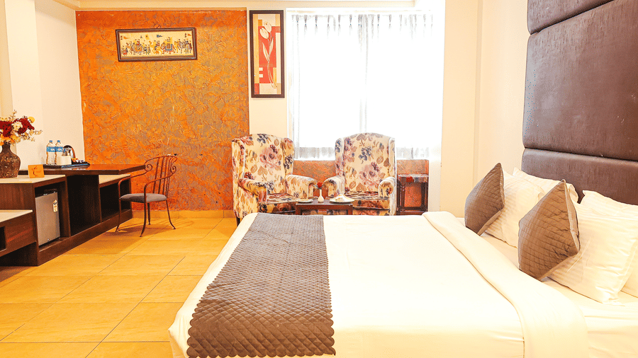 Bright and inviting bedroom with plush bedding and cosy seating area at TGI Apple Inn, Ajmer Road, Jaipur.