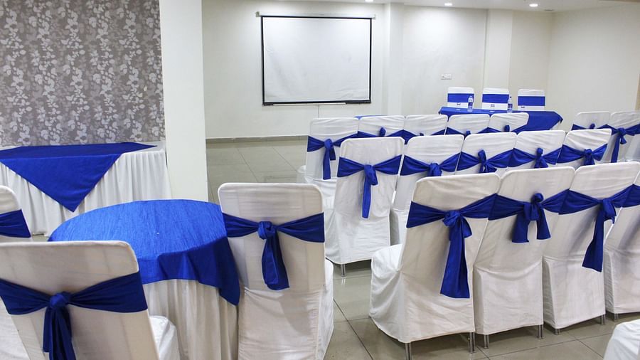 A seminar room with blue and white decorated chairs facing a projection screen - TGI Apple Inn, Jaipur 