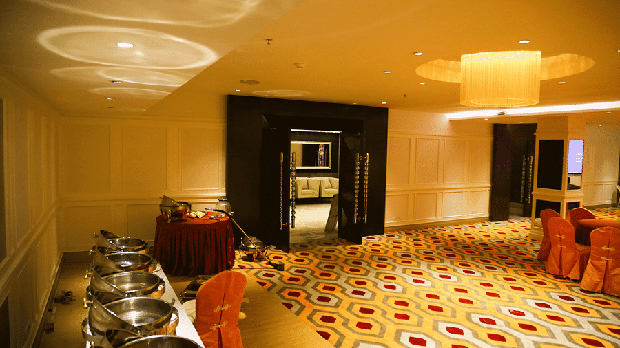A section of a banquet hall with serving dishes lined up and soft lighting patterns on the ceiling - TGI Grand Fortuna, Hosur